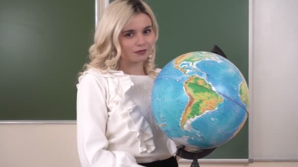 Retrato de una atractiva profesora de geografía en una clase escolar. Joven profesor atractivo - Imágenes, Vídeo