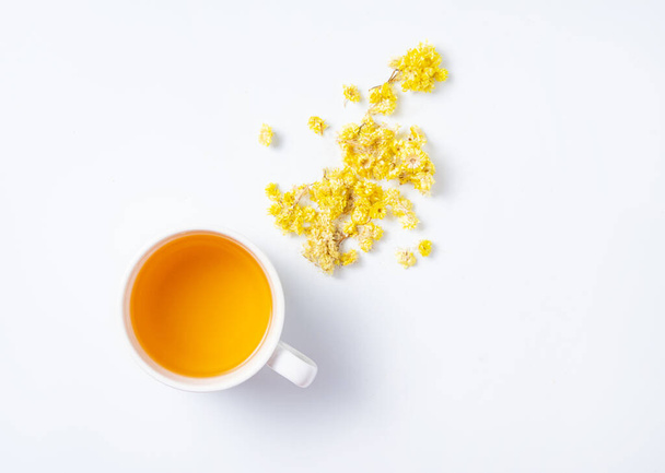  Свежий травяной чай с желтыми цветами на белом фоне. Вид сверху и пространство для копирования - Фото, изображение