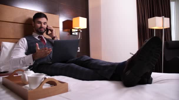 Joyful man talking on cellphone in hotel room - Footage, Video