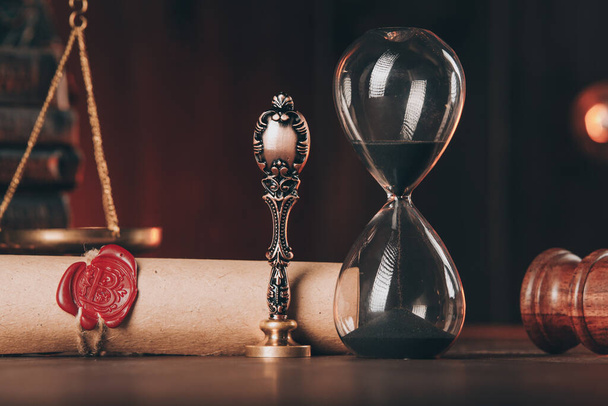 Дерев'яна данина, пісочний годинник і антикварна марка з останньою волею на дерев'яному столі крупним планом
 - Фото, зображення
