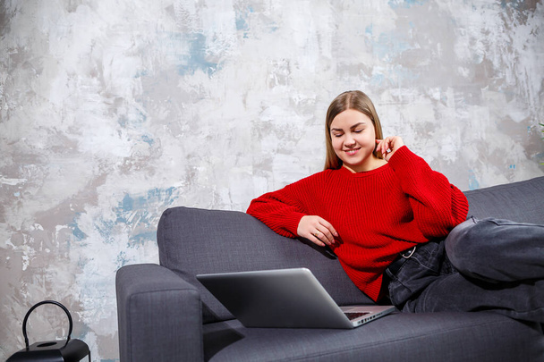 Niezależna kobieta siedząca na sofie w przytulnym wnętrzu domu i pracująca zdalnie na nowoczesnym laptopie, doświadczona kobieta oglądająca webinarium online na stronie internetowej. Praca w domu podczas kwarantanny - Zdjęcie, obraz