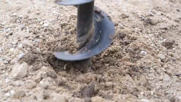 Vue latérale au ralenti de la perceuse tarière à essence à main. La machine est utilisée dans le jardin ou sur le chantier pour percer des trous dans le sol pour tester le sol ou le bâtiment de clôture. - Séquence, vidéo