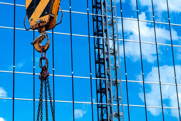 budowa budynków: hak dźwigowy, łańcuchy i kable na tle nieba odbite w szkle - Zdjęcie, obraz