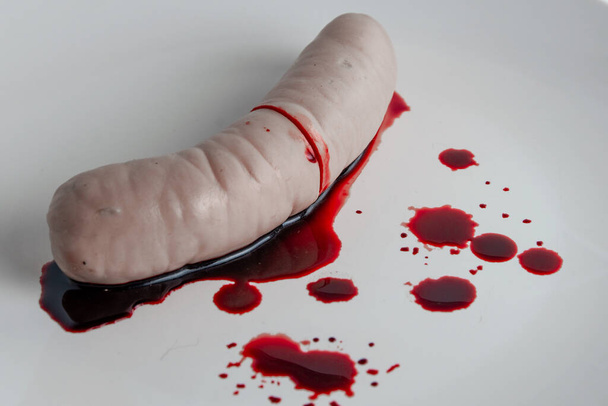 refusal to eat animal meat, concept: bleeding sausage on a white plate, blood splatter, short focus - Photo, Image
