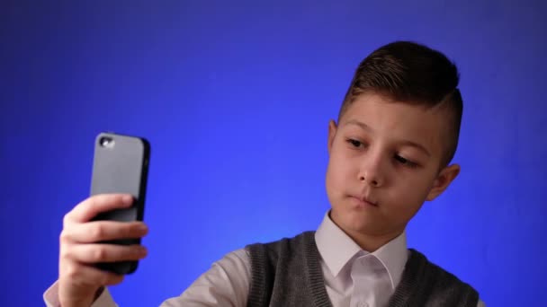 El chico guapo de la escuela se toma una selfie en su teléfono. Niño moderno es fotografiado en su teléfono inteligente. - Metraje, vídeo