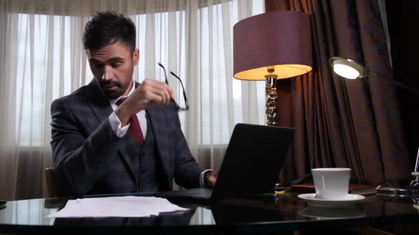 Перегруженный работой бизнесмен расслабляется за столом в офисе - Кадры, видео