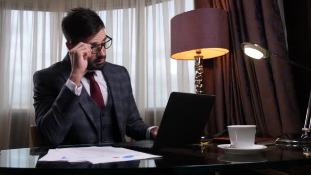 Втомився чоловік в окулярах працює за столом в офісі
 - Кадри, відео