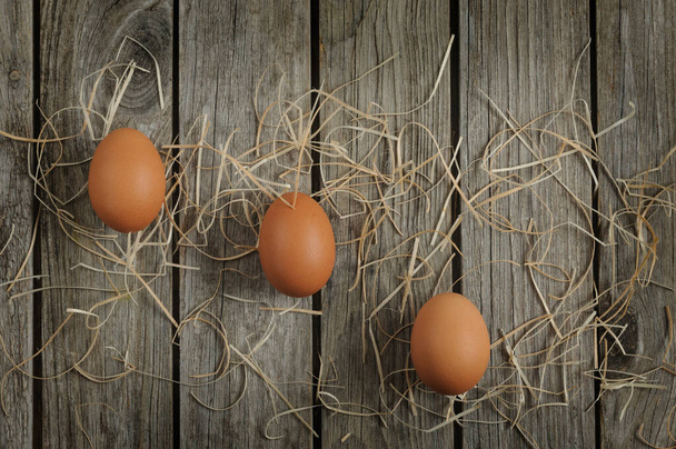 Três ovos de galinha marrom em uma tábua de madeira. Flat lay, vista superior com espaço de cópia - Foto, Imagem