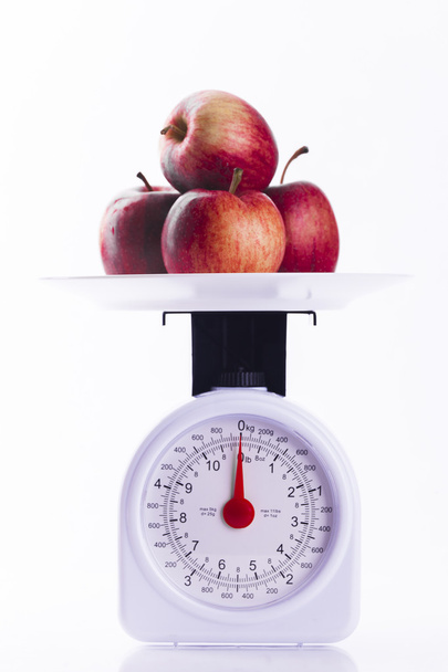 Quatro maçãs vermelhas em balanças de pesagem
 - Foto, Imagem