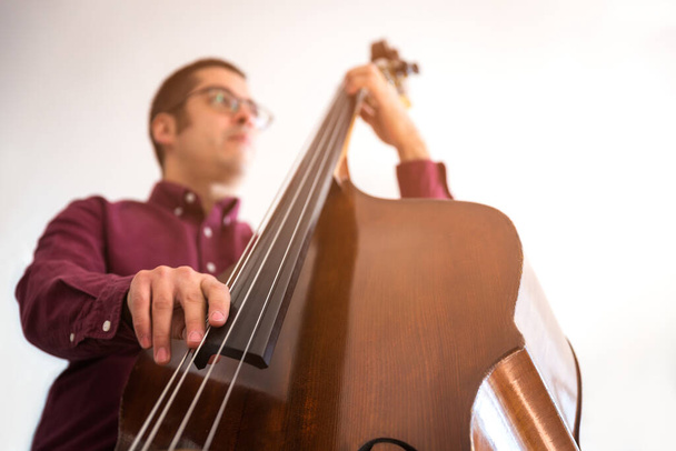 Professional double bass player. Photo shooting in studio. White background - Photo, Image