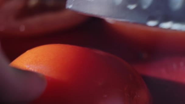 Резка красивого красного помидора с помощью кухонного ножа, капли воды макровидео. Свежий мокрый здоровый помидор для еды и приготовления пищи с органической фермы - Кадры, видео