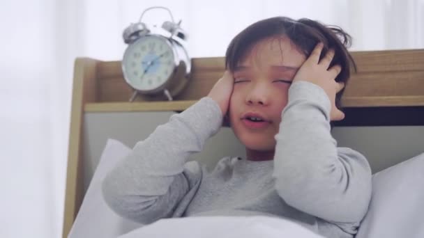 Asiatischer Junge wacht mit schockierendem Gesichtsausdruck auf, nachdem er den späten Wecker auf seinem Bett gesehen hat. - Filmmaterial, Video