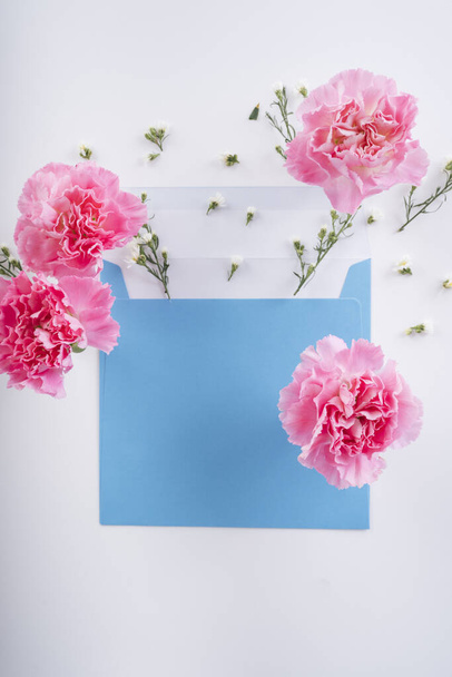 Flor de flor rosa con la maqueta azul encima de la letra adjunta sobre fondo blanco. Vista superior. - Foto, imagen