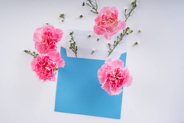 Rosafarbene Blütenblume mit blauer Attrappe auf weißem Hintergrund. Ansicht von oben. - Foto, Bild