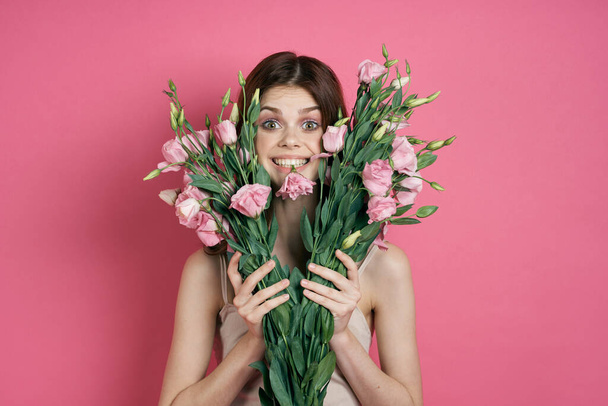 красивая женщина с букетом цветов на розовом фоне в светлом платье макияж модели - Фото, изображение