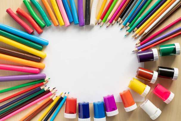 Плоская раскладка цветных красок, маркеров, карандашей и пластилина на столе. - Фото, изображение