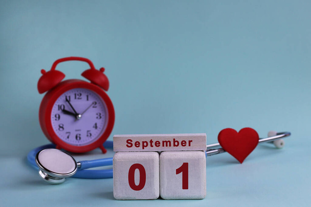 Le 1er septembre. 1er jour du mois. blocs de calendrier en bois blanc avec date, horloge et stéthoscope sur fond bleu pastel. Concentration sélective. concept de santé - Photo, image
