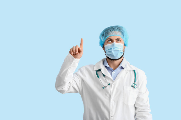 Medico in maschera medica che punta a qualcosa sullo sfondo di colore - Foto, immagini
