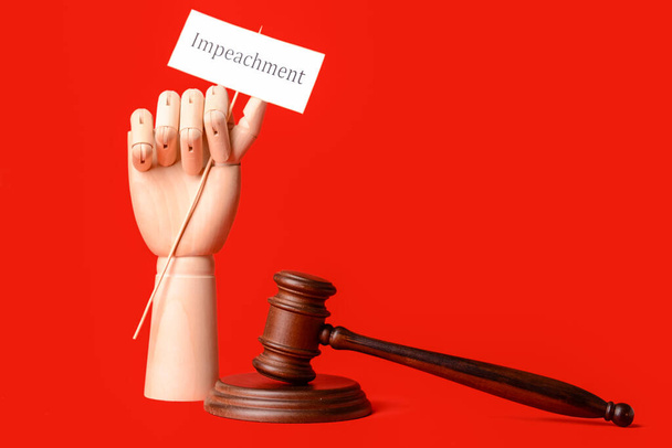 Суддя дав дерев'яній руці папір із словом IMPEACHMENT на кольоровому фоні
 - Фото, зображення