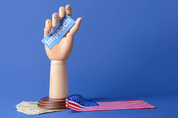 Wooden hand holding paper with word IMPEACH, USA flag and money on color background - Photo, Image