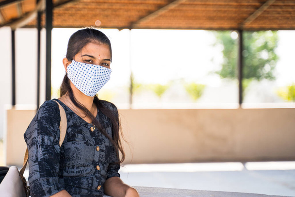 Chica india joven con máscara facial médica mirando cámara en el campus de la universidad con espacio de copia durante la pandemia coronavirus covid-19 - Foto, imagen