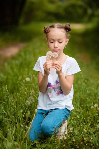 Girl blowing dandelion outdoors in spring field  - Photo, Image