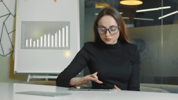 オフィスでタブレットを使っている女性です。ビジネスの女性は小さなオフィスで一人で働く会社の戦略的なタスクを解決します。 - 映像、動画