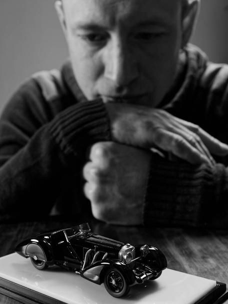 retrato de un coleccionista de modelos de coches retro sobre un fondo negro 2021 - Foto, Imagen