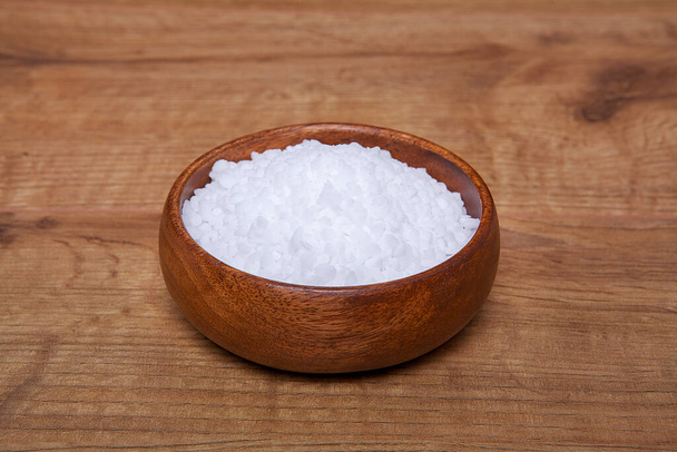  Granules grossiers de roche naturelle ou de sel de mer dans un bol sur une table en bois. - Photo, image