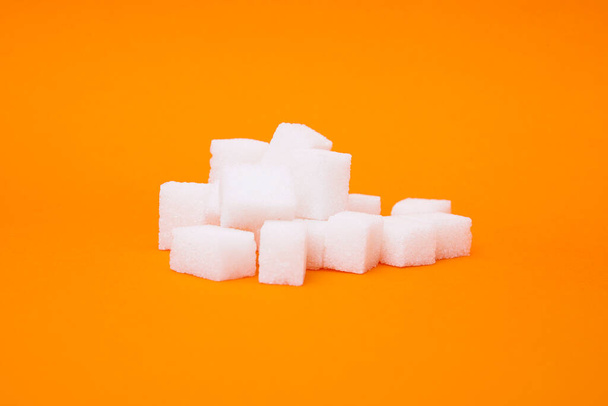 White sugar cube on orange background.   - Photo, Image