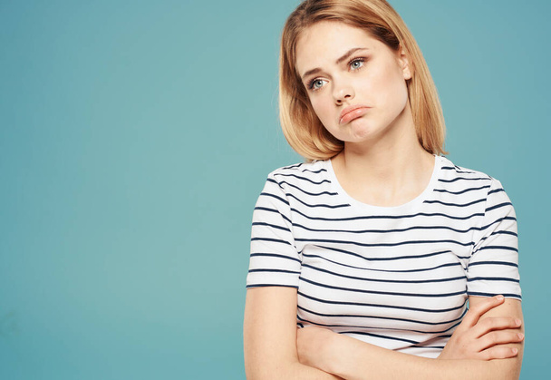 Woman model in striped t-shirt indignant look emotions blue background - Fotografie, Obrázek