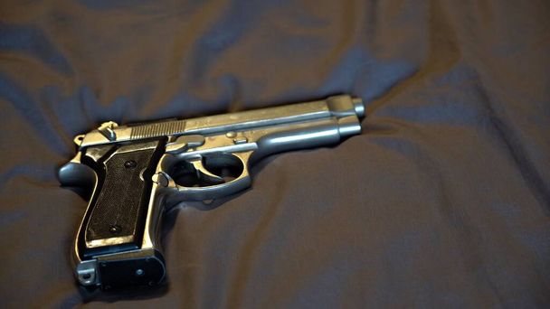 pistol laying on the soft textile background - Photo, Image