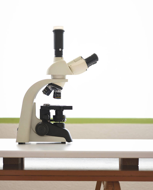 Εργαστήριο με μικροσκόπιο στον πάγκο εργασίας σε λευκό φόντο - Φωτογραφία, εικόνα
