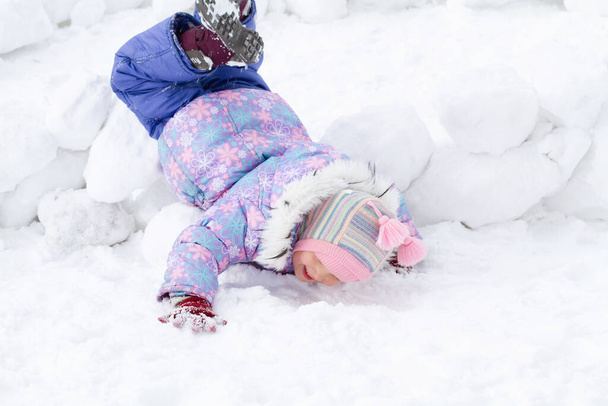 Piccola ragazza carina in tuta invernale gioca nella neve in inverno, affilatura selettiva, sfocatura speciale. - Foto, immagini