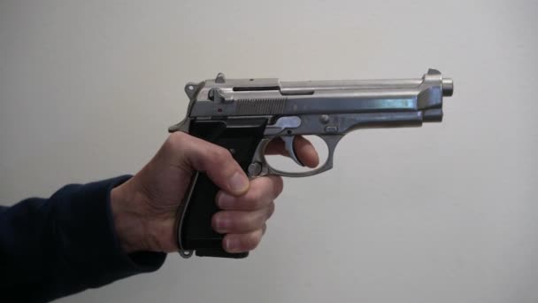 metraje de la mano masculina sosteniendo la pistola y el dedo en el gatillo - Imágenes, Vídeo