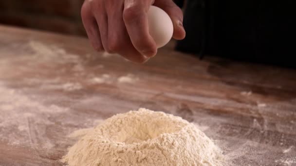 Rozbijanie świeżego jajka na masę mąki. Proces przygotowania ciasta - Materiał filmowy, wideo