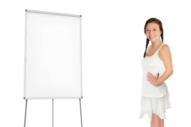 Schöne junge Frau vor einem leeren Flipchart, isoliert auf weißem Studiohintergrund - Foto, Bild