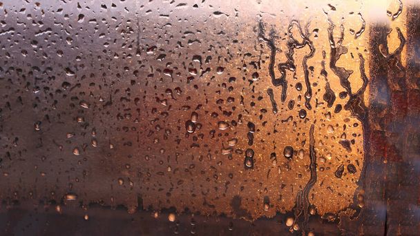 Terli cam pencerede yoğunlaşan damlalar. Soğuk sisli cam. Islak pencere arkaplanı, damlayan damlalarla birlikte doku yoğunlaşması - Fotoğraf, Görsel