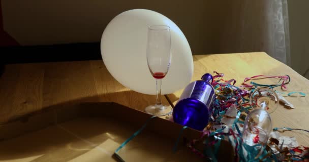 Parti kutlamalarından sonra parti kaosundan sonra parti artıklarını kutlamak için pizza kutusu, boş mavi şişeler, şarap bardağı ve parti süslemeleri olan dağınık ahşap masa.. - Video, Çekim