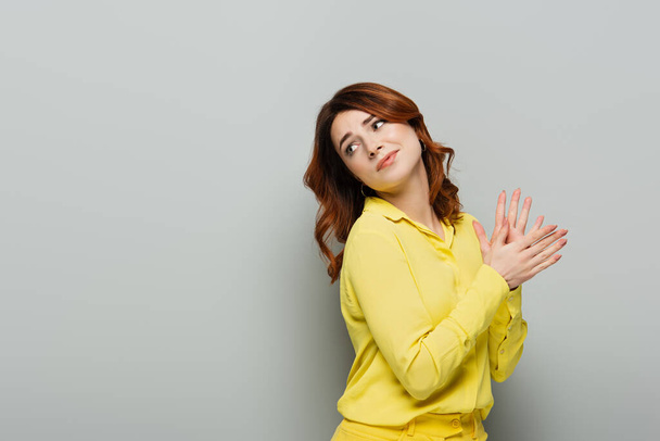 skeptische Frau reibt sich die Hände, während sie grau zurückblickt - Foto, Bild