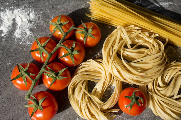 Rauwe pasta ingrediënten op een keukentafel. Bovenaanzicht foto van verschillende soorten pastaand verse groenten. Traditionele Italiaanse gerechten. - Foto, afbeelding