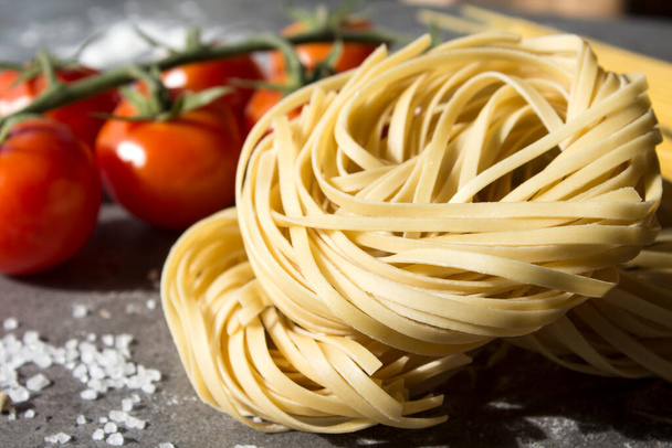Nyers tészta hozzávalók a konyhaasztalon. Top view fotó a különböző típusú pastaand friss zöldségek. Hagyományos olasz élelmiszer. - Fotó, kép