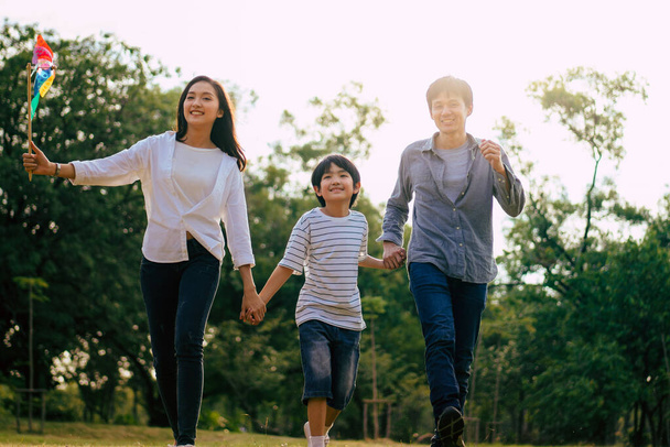 Scène van Aziatische gelukkige familie tijd doorbrengen samen wandelen en ontspannen in het park in de namiddag herfst, concept familie saamhorigheid, warmhartige familie, ouderschap, gelukkige tijd familie uitje. - Foto, afbeelding