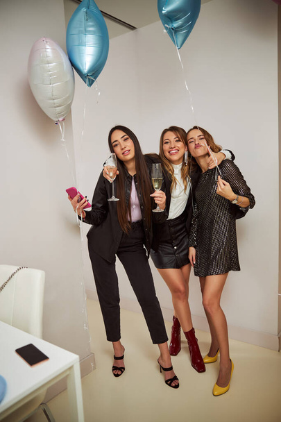 Kolme muodikasta naiset samppanjaa huilut seisoo keittiössä - Valokuva, kuva