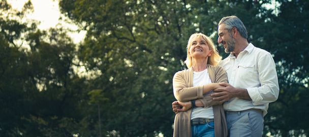 シニアエレガントな白人カップルは、愛を感じ、コピースペースで公園での彼らの記念日を大切にし、幸せな退職した配偶者、よく管理された退職生活の概念. - 写真・画像