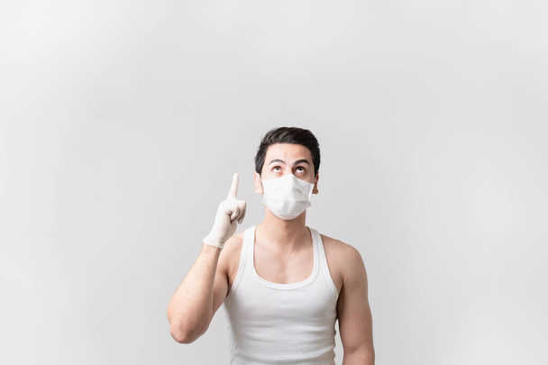 Portrait d'un homme portant un masque et tenant le doigt de son gant jusqu'à l'espace de copie, coronavirus (COVID-19) pandémie, auto-protection, panique et stress, auto-quarantaine, distanciation sociale - Photo, image
