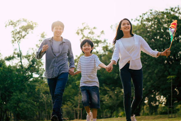 Σκηνή της Ασίας ευτυχισμένη οικογένεια περνούν το χρόνο τους μαζί περπάτημα και χαλάρωση στο πάρκο το απόγευμα του φθινοπώρου, έννοια οικογένεια μαζί, ζεστή καρδιά οικογένεια, την πατρότητα, ευτυχισμένη στιγμή οικογενειακή εκδρομή. - Φωτογραφία, εικόνα