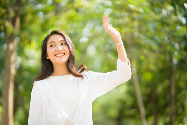 Portret van een gelukkige, succesvolle, aantrekkelijke bebaarde Aziatische vrouw met een grote glimlach met een zelfverzekerde blik naar de camera op een wazige parkachtergrond met kopieerruimte in natuurlijk zonlicht. - Foto, afbeelding