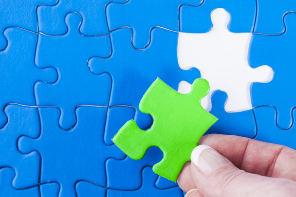 Woman's hand placing missing piece in Jigsaw puzzle  signifying  - Photo, Image