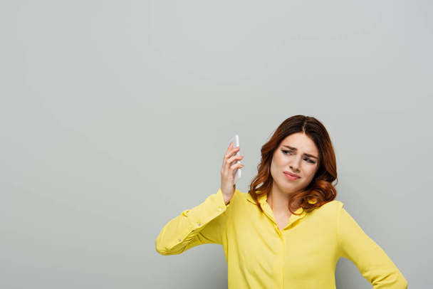 nespokojená žena distancování od smartphonu během konverzace na šedé - Fotografie, Obrázek